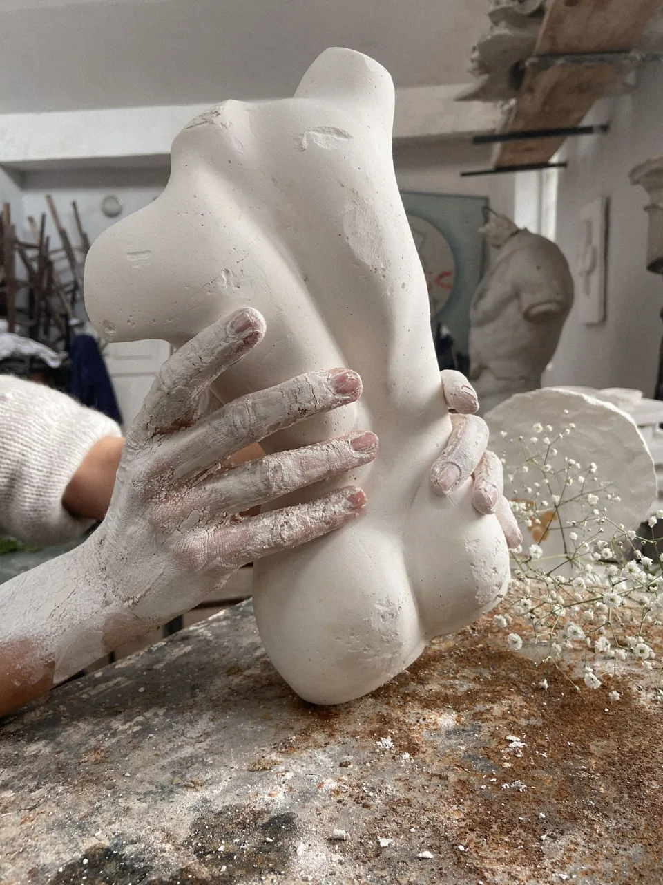 Des mains couvertes d’argile façonnent une sculpture dans un atelier d’artiste